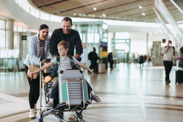 Couple pushing trolley with their child at airport