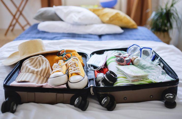 An open suitcase packed for holiday on bed at home