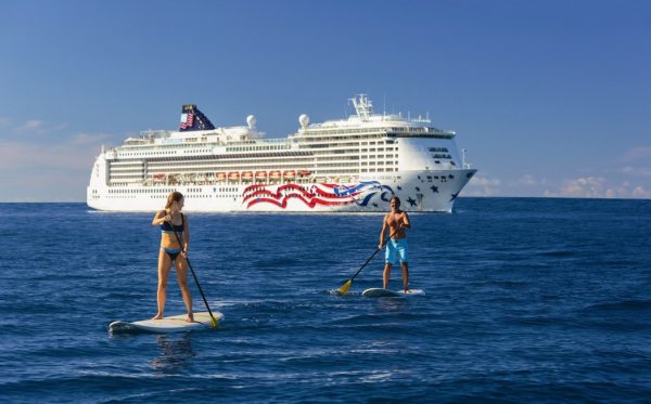 Norwegian Cruise Lines Pride of America with two passengers paddleboarding in the ocean in front